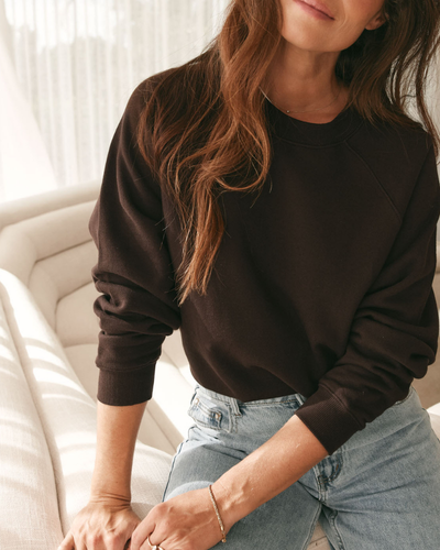 dark brown crew neck sweatshirt with raglan sleeves paired with light blue denim jeans for a relaxed vibe