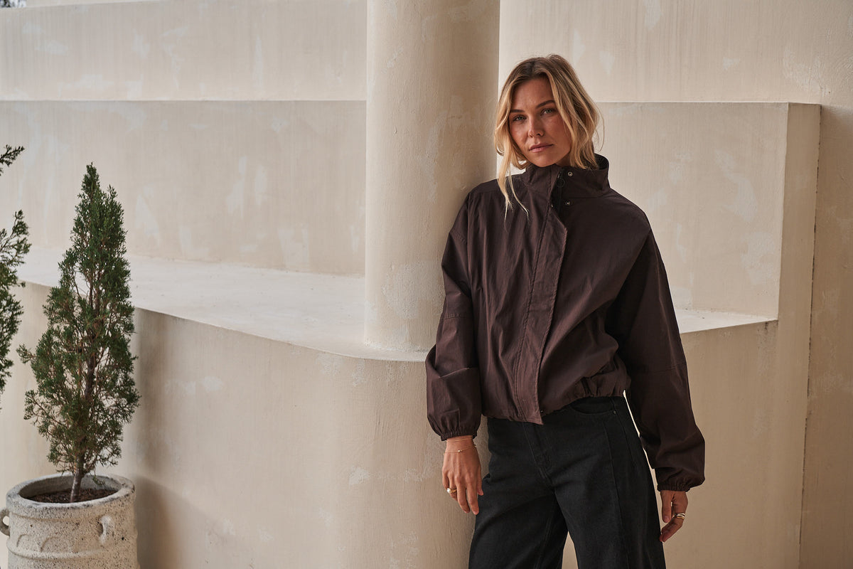 Dark brown cropped jacket with a high collar, front zip and gathered cuffs